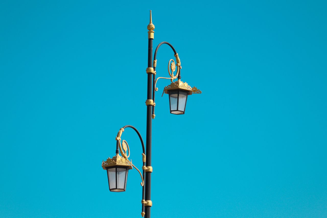 Vintage street lamp with ornate details set against a clear blue sky.