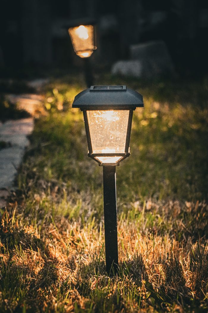 Warm glow of a garden solar light illuminating a pathway at dusk, creating a cozy atmosphere.